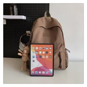 Detailansicht eines lässigen minimalistischen braunen Rucksacks mit niedlichem Bärenanhänger.