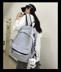 Detail shot of a minimalist grey canvas backpack with cute bear pendant for campus style.