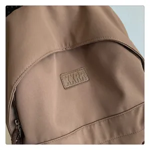 Detailansicht des schlichten Freizeitrucksacks in Braun mit einem Markenaufnäher.