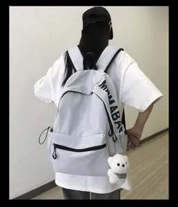 Detailed view of casual minimalist solid color backpack with side letter print and cute bear pendant.