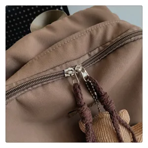 Nahaufnahme der khakifarbenen Freizeit-Schulrucksack-Details mit Metallverschlüssen und Bär.