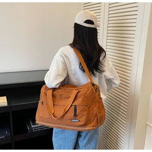 Detail view of large capacity travel duffle bag in brown, showing shoulder strap and side pocket.
