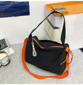 Detail view of the black and orange gym fitness shoulder bag featuring adjustable straps and pockets.