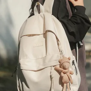 Einfacher beiger Schulrucksack für Studenten, lässiger Alltags-Rucksack mit süßem Bärenanhänger.