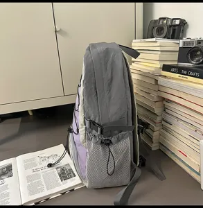 Vista dettagliata dello zaino con coulisse grigio, tasca laterale in rete e cinghie regolabili.