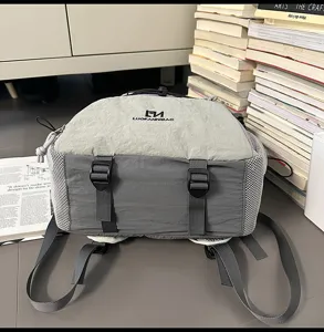 Dettaglio zaino grigio con lacci coulisse, fibbie anteriori e tasche laterali in rete.