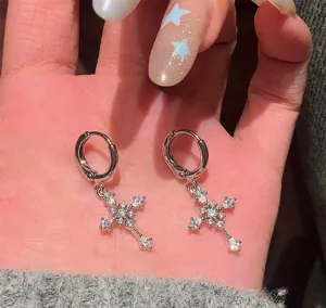 Close up detail of sparkling silver cross zircon hoop earrings dangling beautifully on hand.