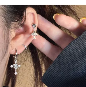 Close-up detail of luxury cross zircon hoop earrings sparkling on ear, minimalist punk jewelry!