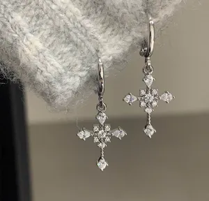 Detailed close-up view of shimmering zirconia cross drop earrings, stunning spark and elegance.
