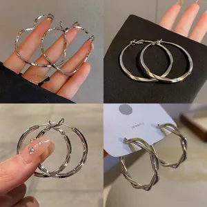 Detailed view of trendy geometric twisted hoop and heart earrings, versatile metallic design.