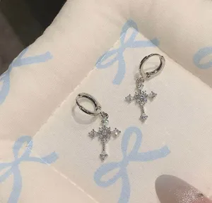 Close-up of sparkling silver cross zirconia dangle earrings, detailed pave crystal design.