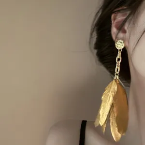 Detailed close-up of vintage gold feather tassel earrings, elegant and unique fashion jewelry.
