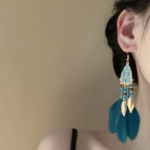 Closeup detail view of bohemian turquoise feather tassel earrings featuring intricate bead charms.