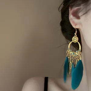 Bohemian gold tone feather tassel earrings with turquoise accents and retro vintage detail design.