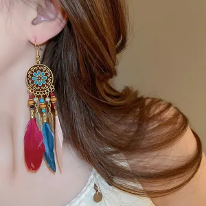 Close-up detail shot of bohemian feather tassel earrings showcasing intricate metal carved patterns.