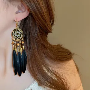 Close-up of bohemian style black feather tassel earrings with vintage metal filigree design.