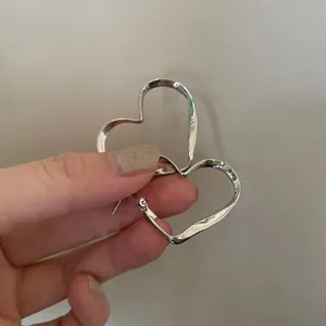 Detailed view of trendy irregular twisted heart hoop earrings, stylish silver tone design.