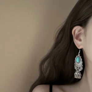 Close-up detail of vintage bohemian turquoise tassel drop earrings, ethnic style silver metal.