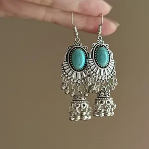 Close-up detail of vintage bohemian turquoise long dangle earrings, antique silver-toned metal fringe.