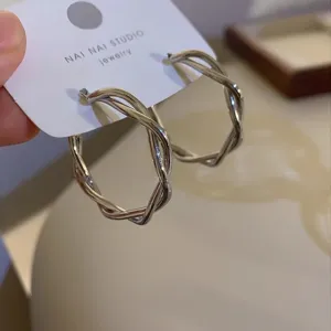 Twisted geometric hoop earrings for women, stylish silver metal irregular minimalist jewelry detail.
