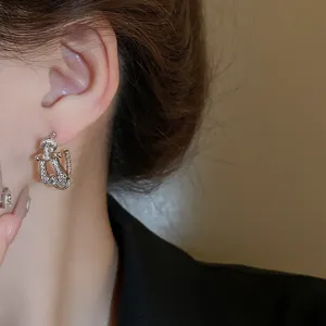Detailed close-up of sparkling rhinestone geometric earrings worn on ear, elegant silver style.