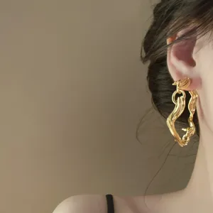 Detailed close-up view of the abstract wavy metallic gold statement earring worn gracefully.