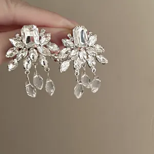 Close-up detail of silver-tone rhinestone cluster earrings with hanging crystal teardrops.