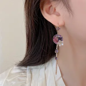 Dettaglio orecchini pendenti fiore zircone viola, design goccia di cristallo brillante.
