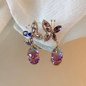 Primo piano di orecchini a farfalla sfumati in viola con dettagli in zircone brillante.