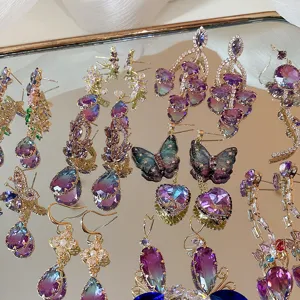 Primo piano di eleganti orecchini pendenti in zircone viola e graziosi orecchini a farfalla.