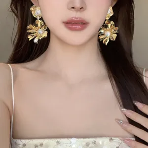 Close-up shot of elegant gold metallic flower pearl earrings, stylish fashion jewelry detail.