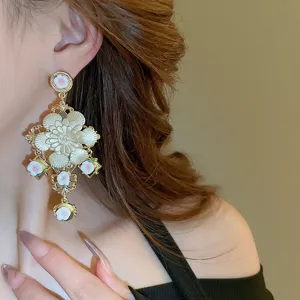 Detail view of the exaggerated gold floral tassel earring worn on ear, elegant design.
