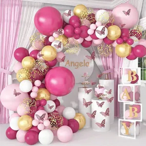 Gorgeous pink and gold balloon arch backdrop scene with butterfly decor for party setup.
