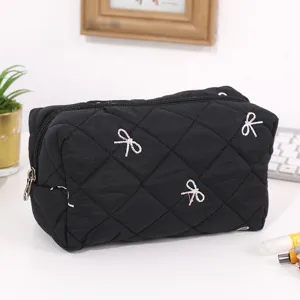 Close-up of black quilted cosmetic bag with cute embroidered bow details for daily storage.