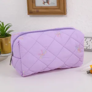 Quilted purple cosmetic bag with cute embroidered bows, perfect for travel and daily use.