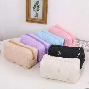 Quilted cosmetic bag detail featuring cute embroidered bows, multi-color storage pouch.