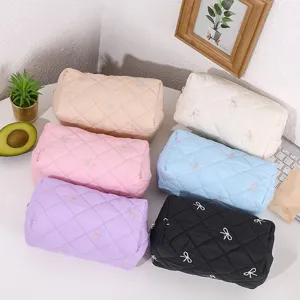 Quilted cosmetic bag with embroidered bow design, multi-color portable makeup pouch detail.