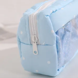Close-up detail of light blue polka dot pencil pouch with clear window and white zipper.