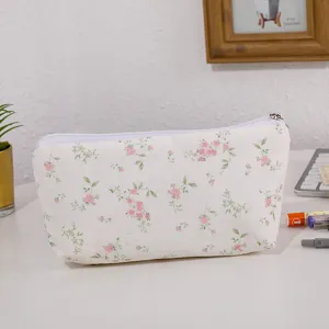 Primo piano dettagliato dell'astuccio floreale sulla scrivania bianca con tessuto e zip.