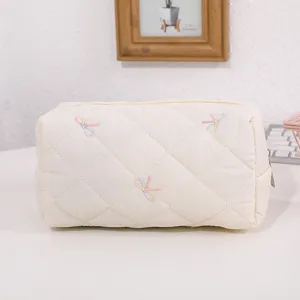 Detailed view of quilted cosmetic bag featuring cute colorful bow embroidery, soft fabric.
