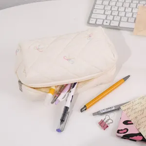 Detail shot of quilted cosmetic pouch featuring colorful embroidered bows, soft texture.