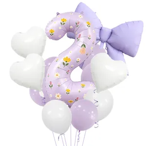 Détails rapprochés du ballon en aluminium chiffre violet, nœud et set de fête.