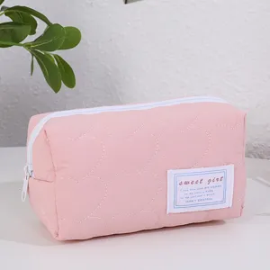 Détail de trousse de maquillage cœur matelassé rose, pochette cosmétique portable.