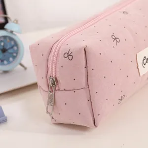 Close-up detail of the pink canvas pencil case with cute bow and dot patterns for students.