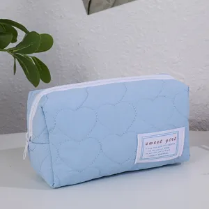 Gros plan détaillé de la trousse de maquillage matelassée bleue claire avec motif cœur.