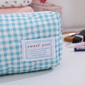 Sac de maquillage matelassé à carreaux bleus et blancs en gros plan, jolie pochette cœur.