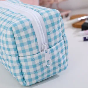 Gros plan trousse maquillage carreaux bleu et blanc avec détail cœur matelassé et fermeture zippée.