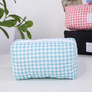 Vue détaillée du sac cosmétique à carreaux matelassé bleu avec motif de cœur et fermeture éclair.