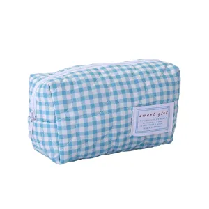 Vue détaillée de la trousse de maquillage matelassée à carreaux bleus et blancs.