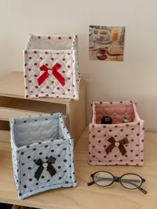 Quilted square storage basket with cute bow and polka dot pattern for tidy desk organization.